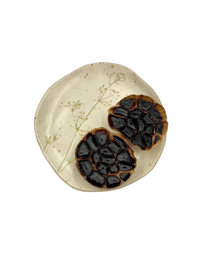 deux demi têtes d'ail noir présentées sur une assiette