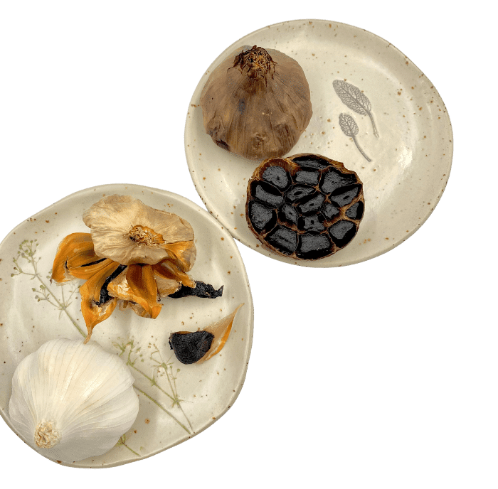 deux demi têtes d'ail noir présentées sur une assiette
