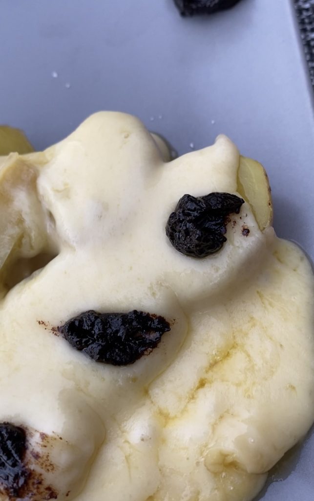Idée de recette qui présente de la raclette avec de la crème d'ail noir