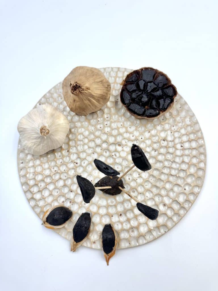 présentation sur assiette de l'ail blanc cru qui a subi la maturation pour devenir ail noir