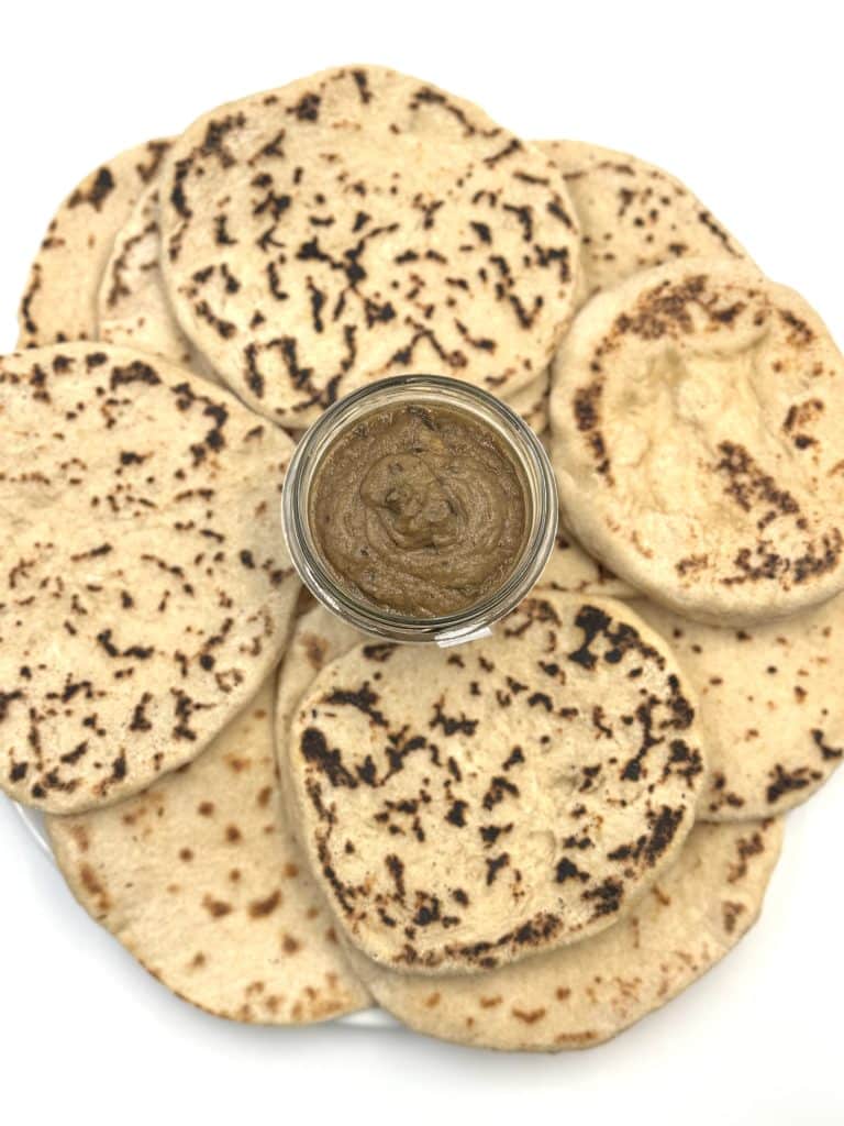 Assiette qui présente des naans avec un pot de caviar d'aubergines pour illustrer une recette