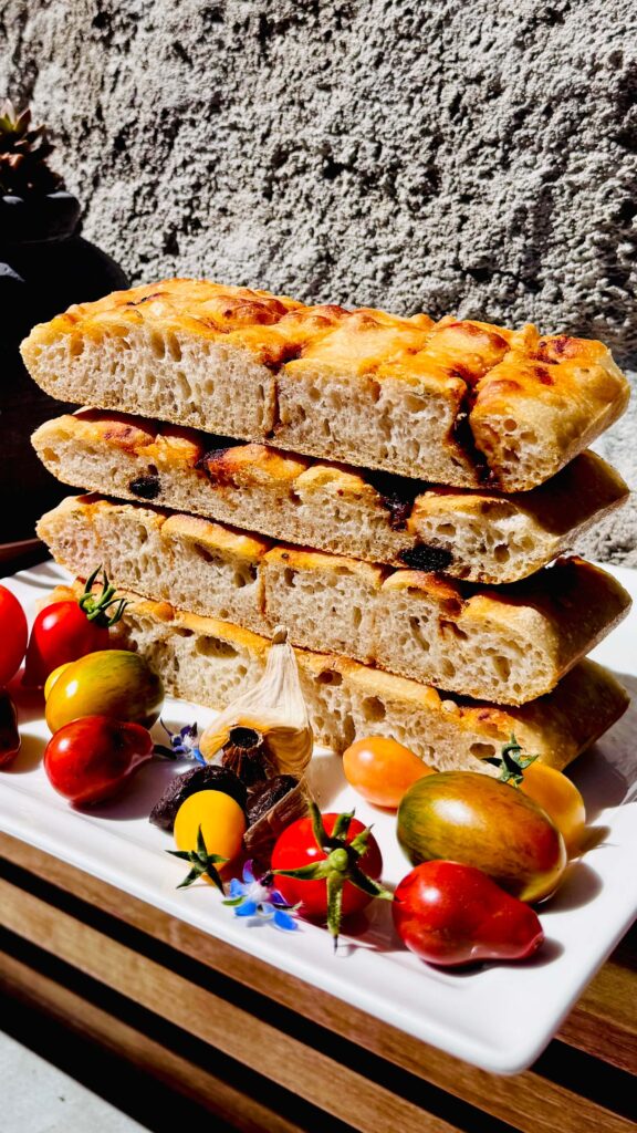 focaccia maison découpée avec tomates et ail noir